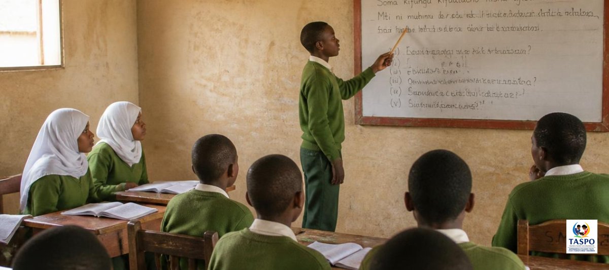 A pupil pointing at a whiteboard while classmates watch in a Tanzanian classroom
